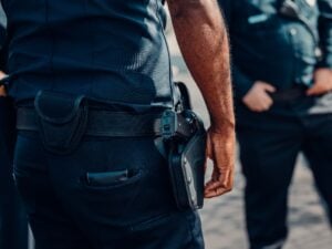 Can Your Criminal Record Be Used Against You at a Traffic Stop? 2 Close-up of a police officer’s duty belt and holstered firearm with other officers in the background.