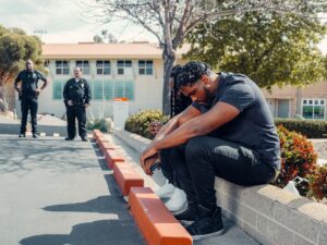 How Long Can Police Keep You at a Traffic Stop in California? 2 Two men sitting on a curb while police officers stand nearby.
