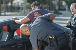 How to Refuse a Police Search of Your Car (and Take Back Consent) 1 Police officer conducting a pat-down of a man beside a car while another officer observes.