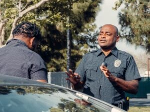Can Your Criminal Record Be Used Against You at a Traffic Stop? 1 Police officer speaking with a man beside a vehicle during a roadside stop.