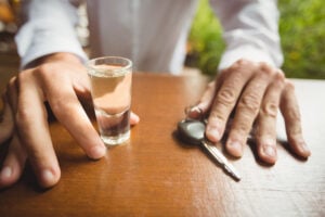 Is Being Drunk in Public a Crime in California? What Penal Code § 647(f) Really Requires 2 Shot glass of alcohol and car keys on a table in front of a person.