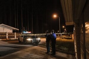 Can You Sue for Being Falsely Arrested? Understanding Cop Immunity 2 Police officers speaking with a person near a patrol car and police tape at night.