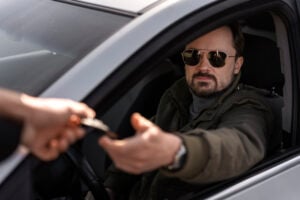Can Police Arrest You for Asking If They Have Reasonable Suspicion? 2 Driver handing a card or document to someone through the open car window.